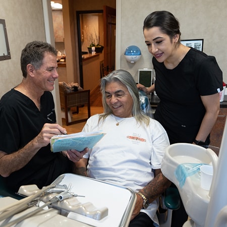 Dr. Robert Weber and his female dental assistant explaining dental care to an older man