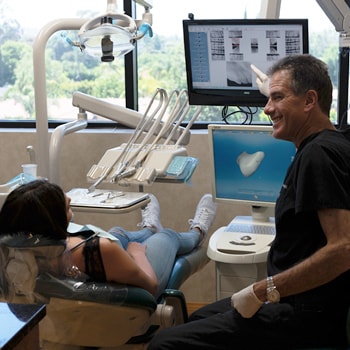 Dr. Weber pointing at a screen while a patient lies on the dental chair
