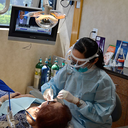 One of our Encino specialists performing surgery on an older woman who is lying in the dentist's chair